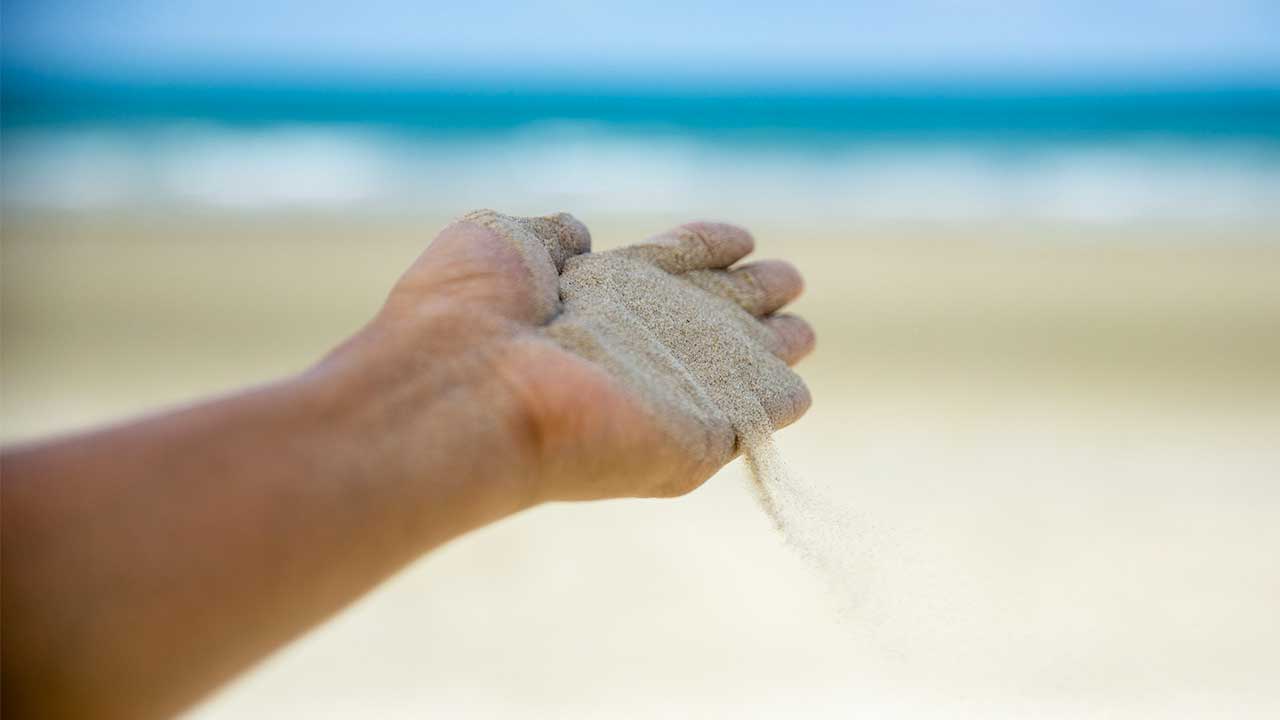 Sand rieselt von einer Hand