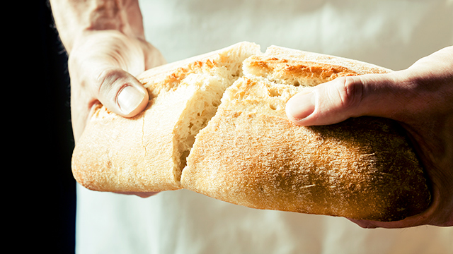 Hände brechen Brot