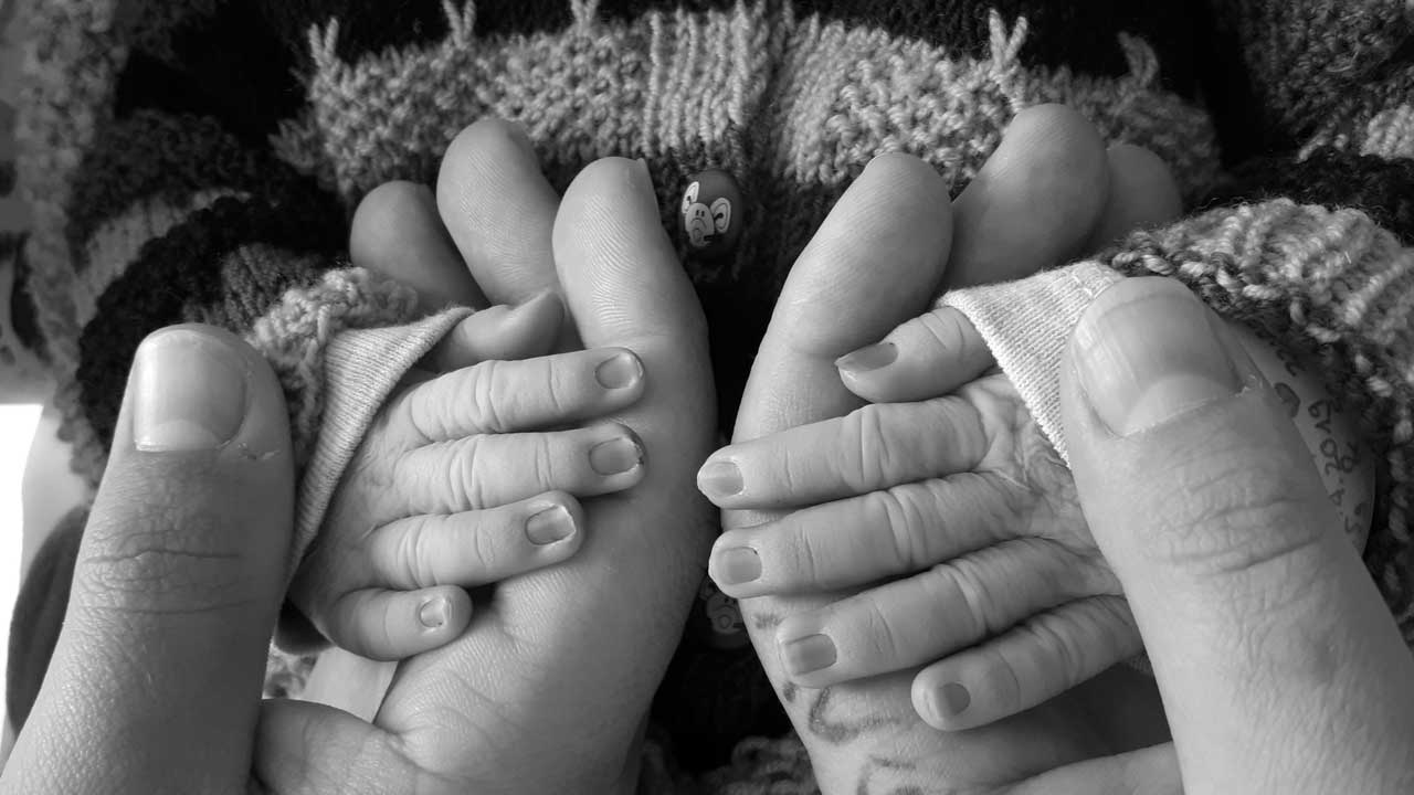 Hände eines Erwachsenen halten die Hände eines Babys