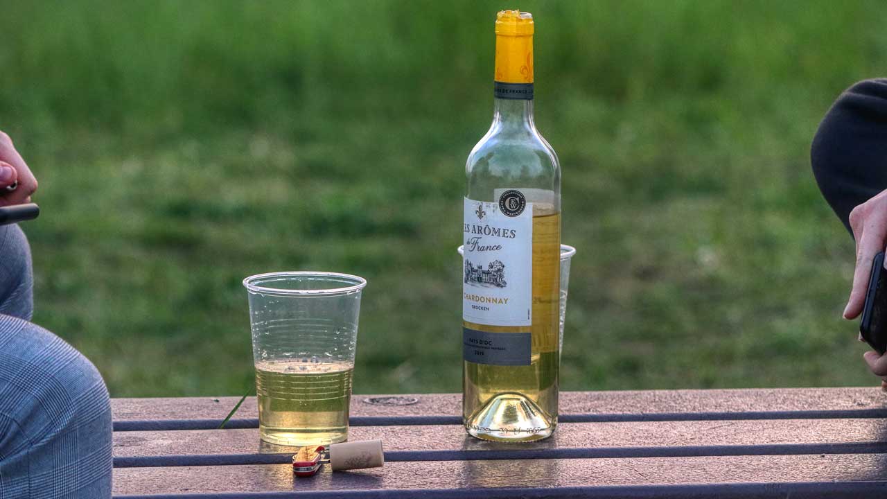 Auf einem Sitzbank steht eine Flasche Weisswein mit zwei Bechern