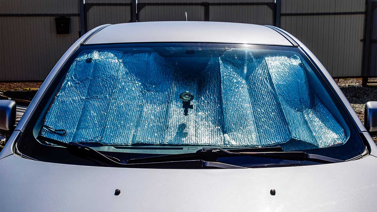 Windschutzscheibe eines Autos mit einem Sonnenschutz hinter der Scheibe
