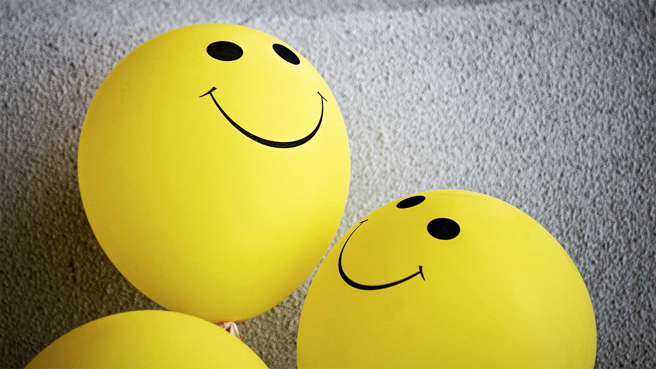 Ein gelber Smiley-Ballon bewundert den anderen