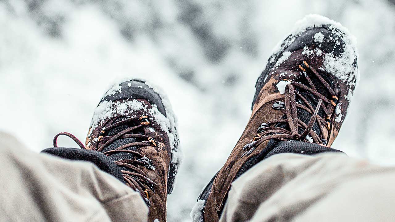 Blick auf Beine mit Winterschuhen, Schnee im Hintergrund