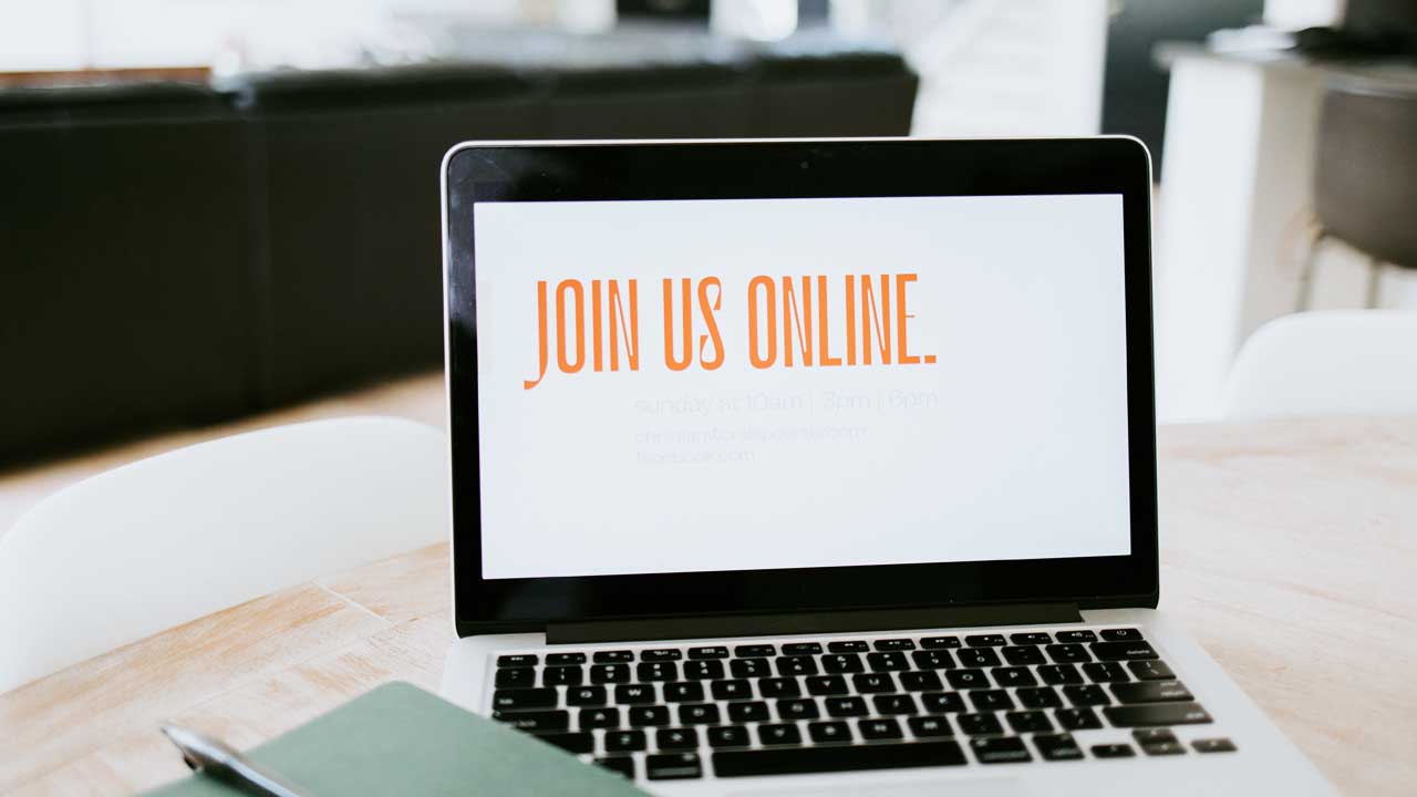 Laptop auf einem Wohnzimmertisch, auf dessen Bildschirm steht «Join us online»