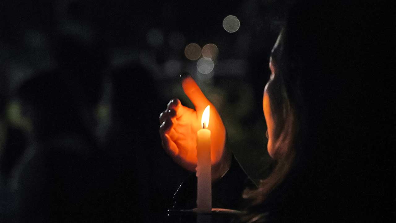 Frau hält Kerze in der Dunkelheit