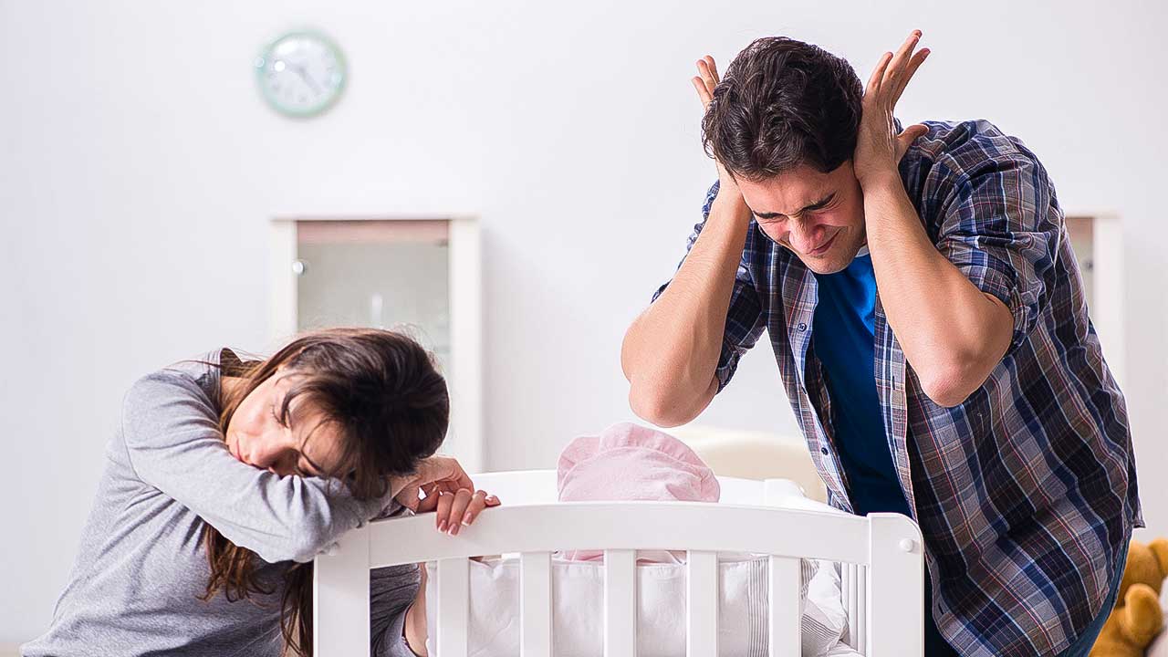 gestresste und müde Eltern an einem Babybett