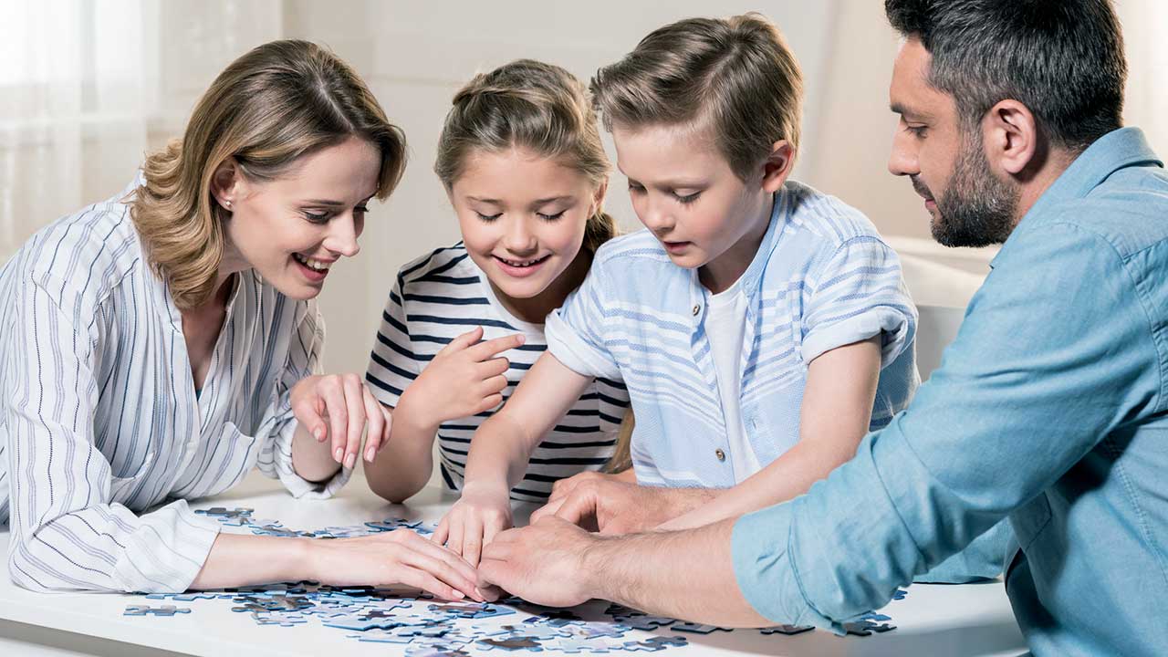 Familie mit Eltern und zwei Kindern hat Spass beim Puzzlespiel