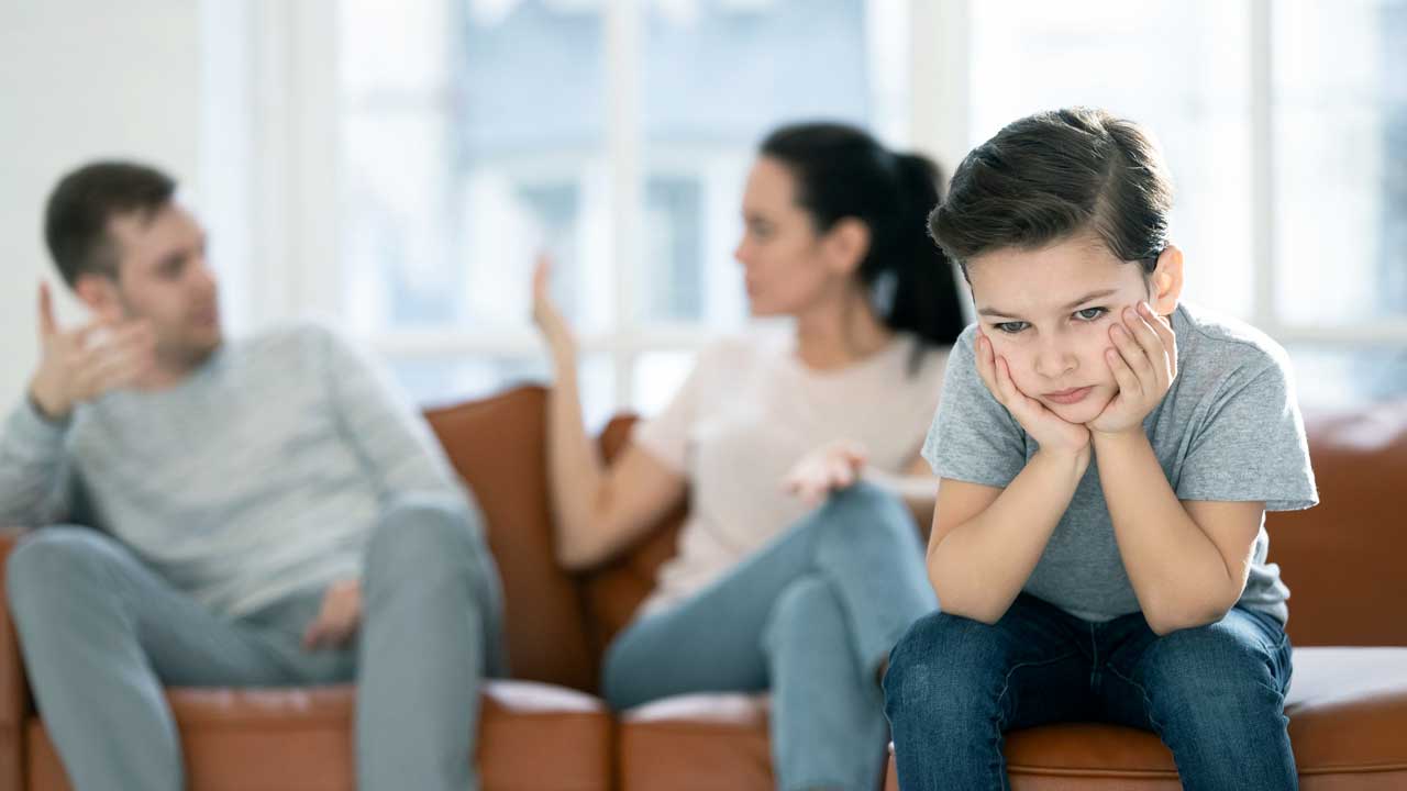 Eltern streiten, Junge sitzt frustriert vor ihnen