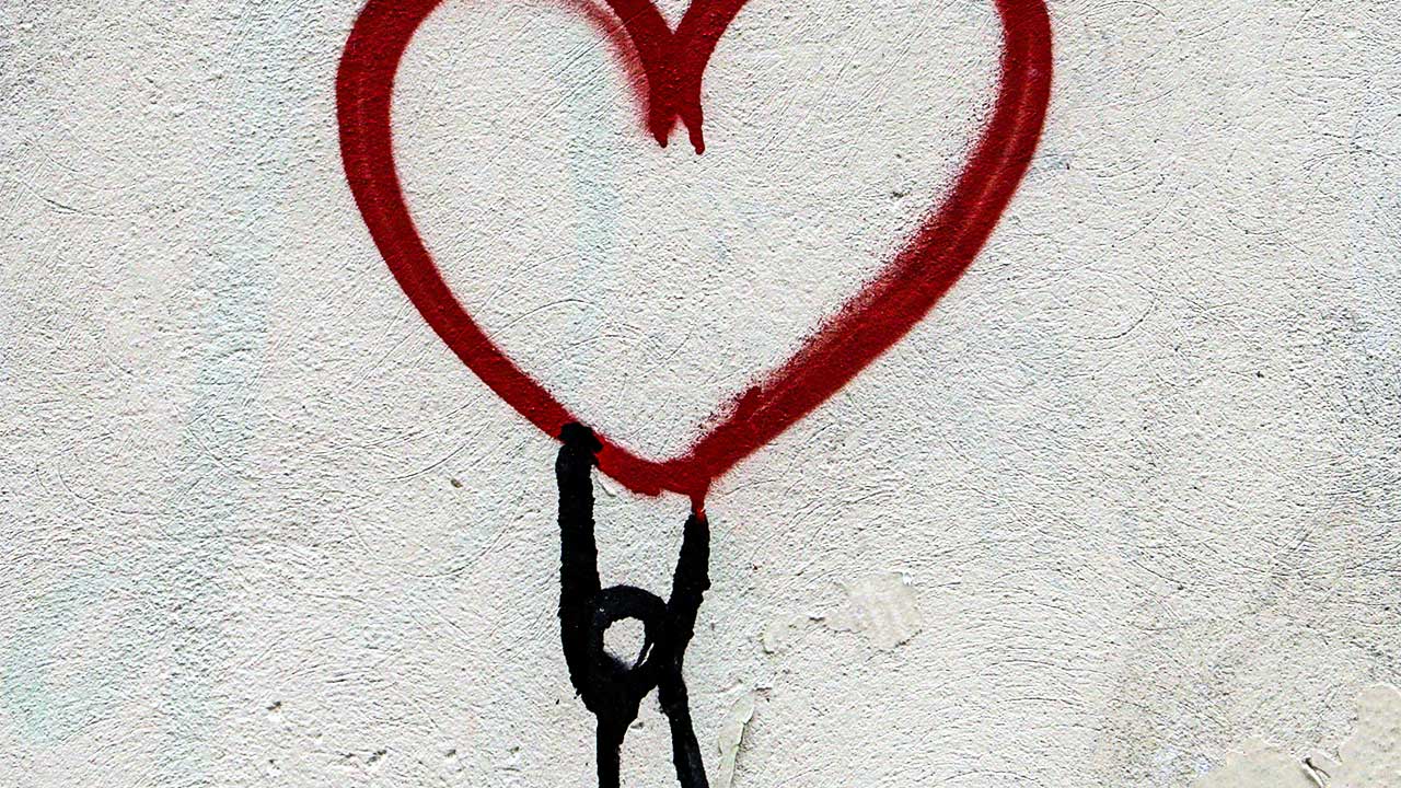 Graffiti mit Figur, welche ein grosses Herz nach oben hält