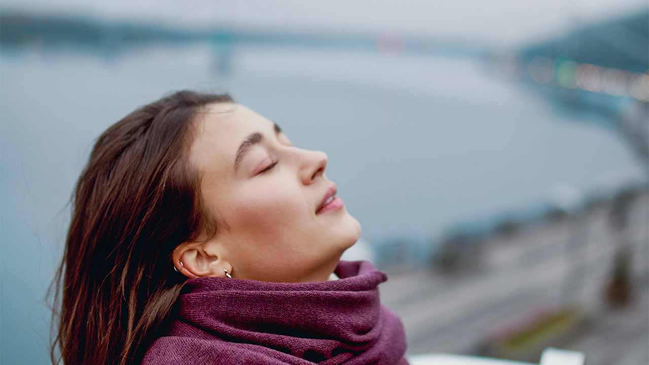 Junge Frau blickt mit geschlossenen Augen nach oben.