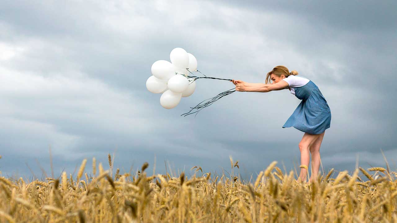Frau hält Ballone gegen den Wind