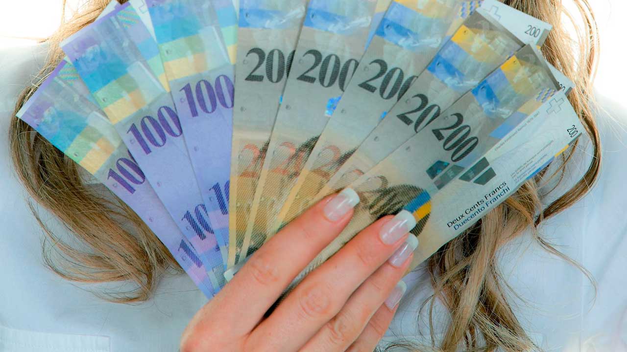 weibliche Hand hält Geldscheine von Schweizer Franken