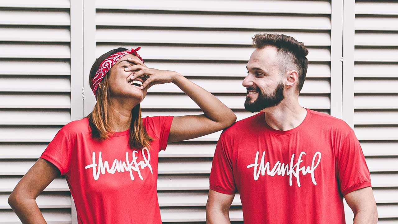 Frau und Mann sind fröhlich und tragen ein Thankful-T-Shirt