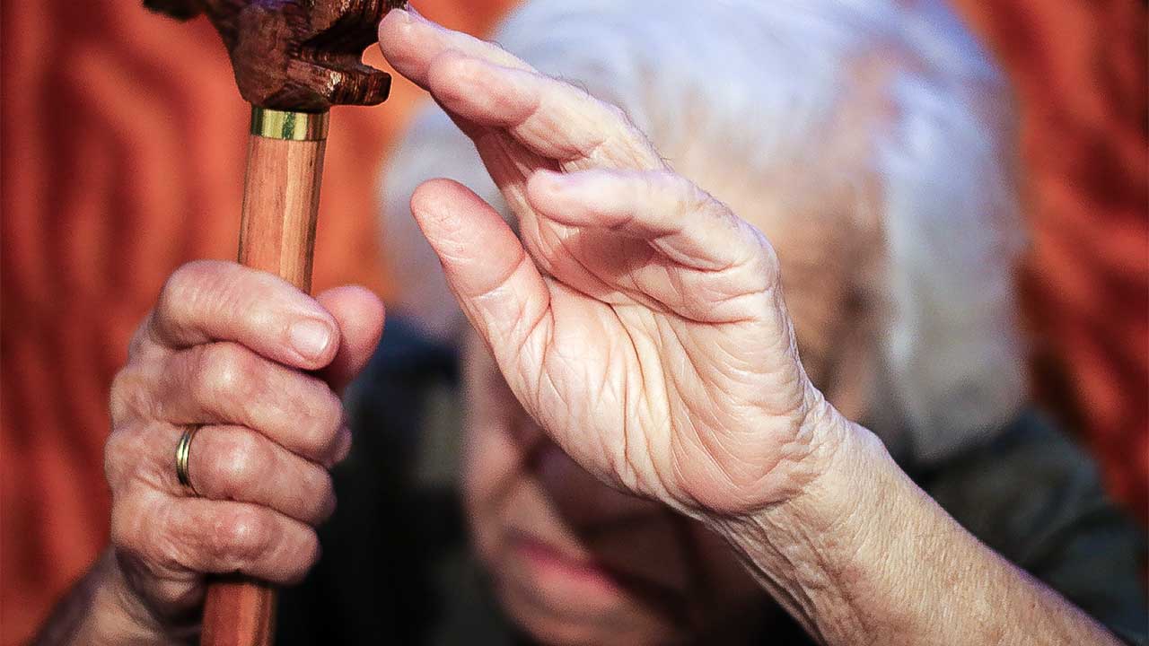 Seniorin hält zum Schutz eine Hand vor ihre Gesicht