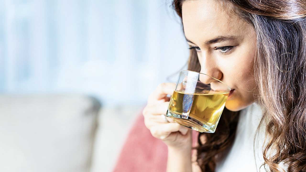 Frau trinkt aus einem Teeglas Tee
