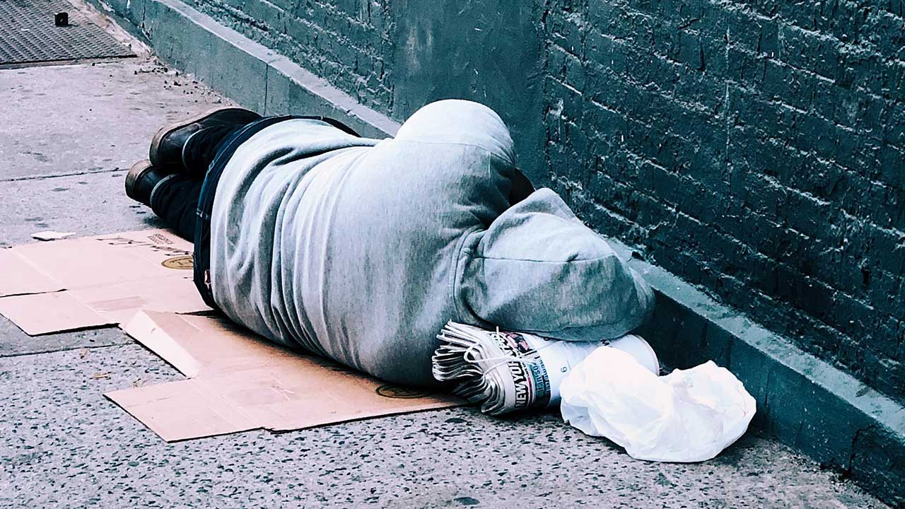 Obdachloser liegt oder schläft an einer Wand