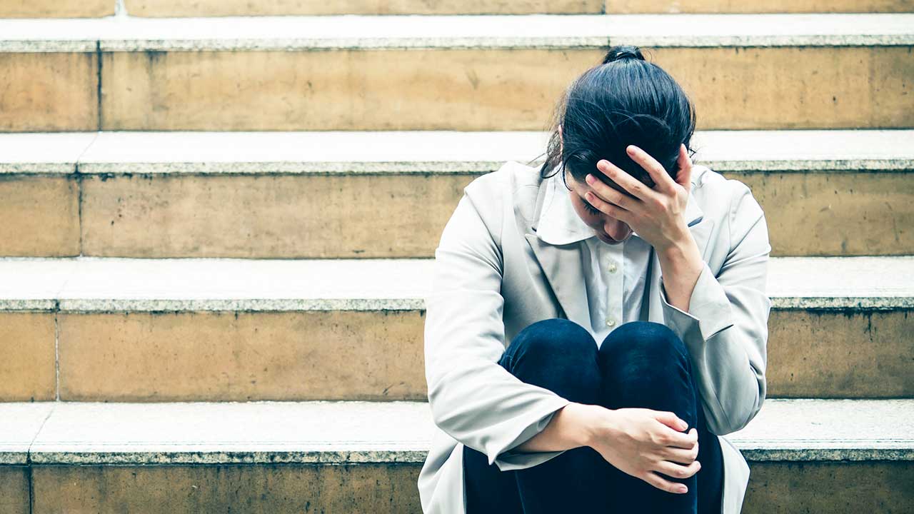Geschäftsfrau sitzt auf einer Treppe, niedergeschlagen und getroffen