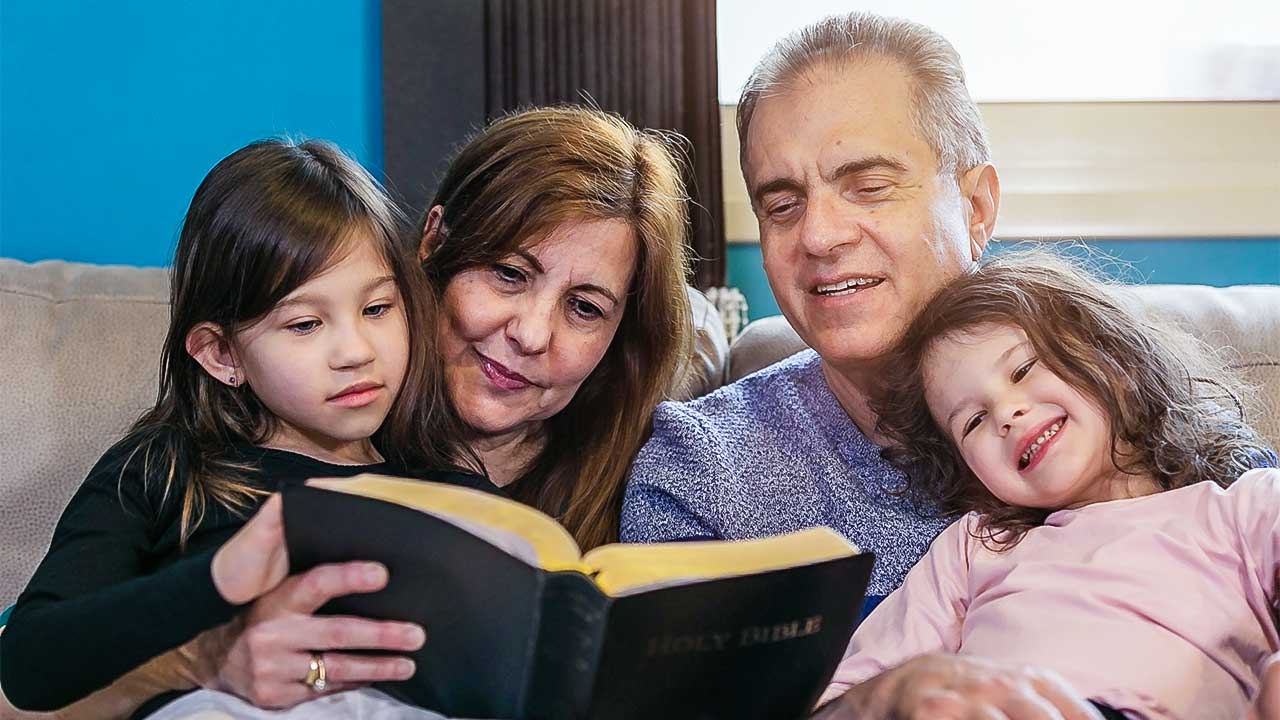 Grosseltern lesen ihren beiden Enkelinnen aus der Bibel vor