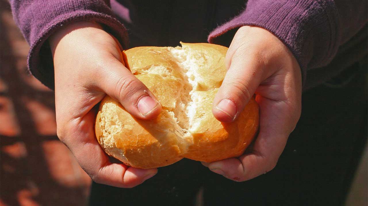 Zwei Hände brechen ein Brötchen