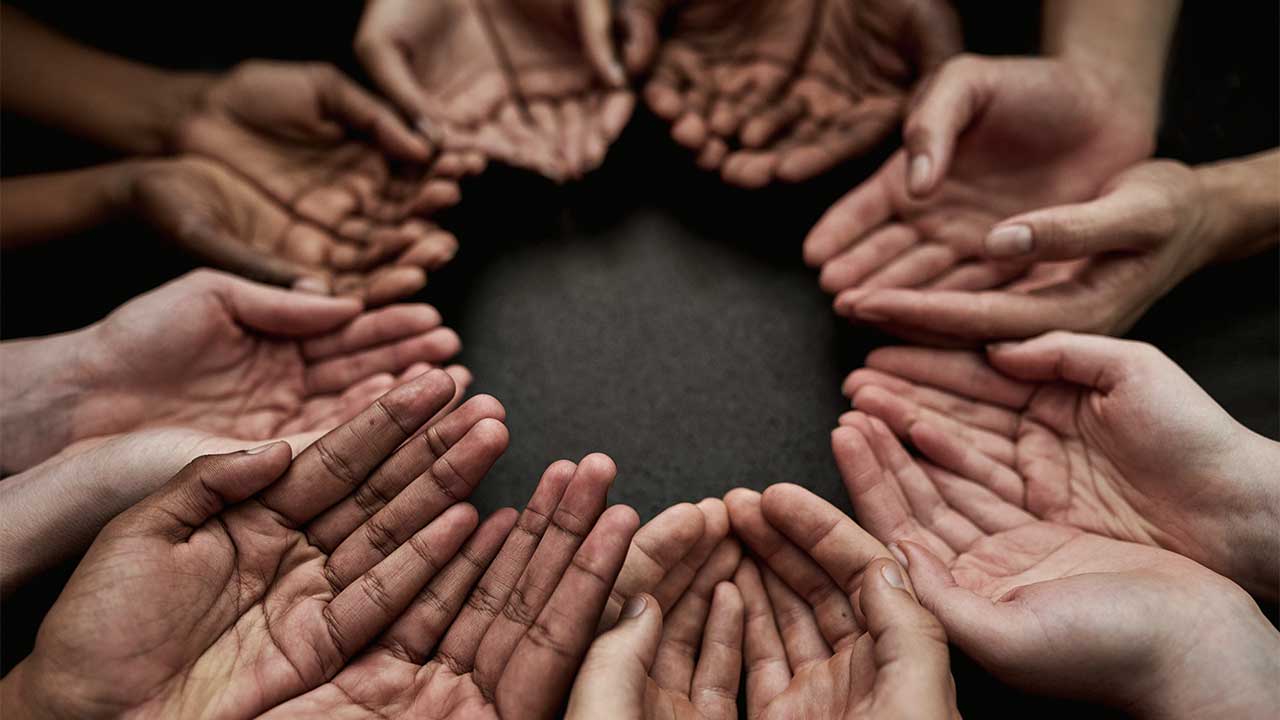 mehrere Händepaare bilden einen Kreis als Zeichen von Zusammenhalt und Gemeinschaft
