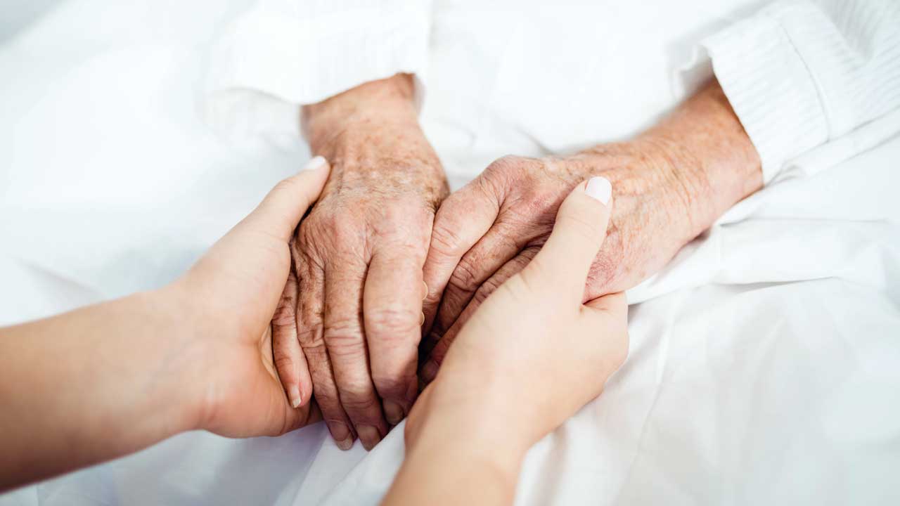 Jüngere Hände umfassen die Hände einer älteren Person