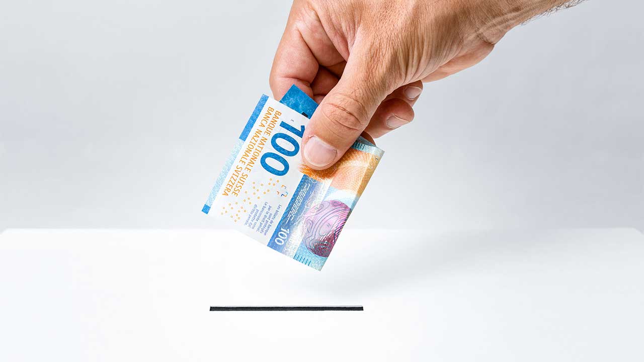 Hand mit einer 100-Franken-Note, welche gespendet wird