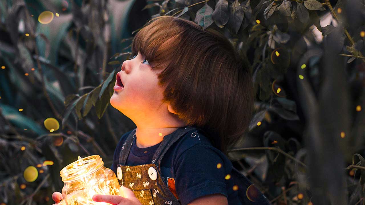 Kind mit einem beleuchteten Glas blickt hoch