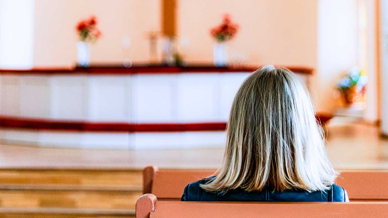 Frau sitzt allein in einer Kirche