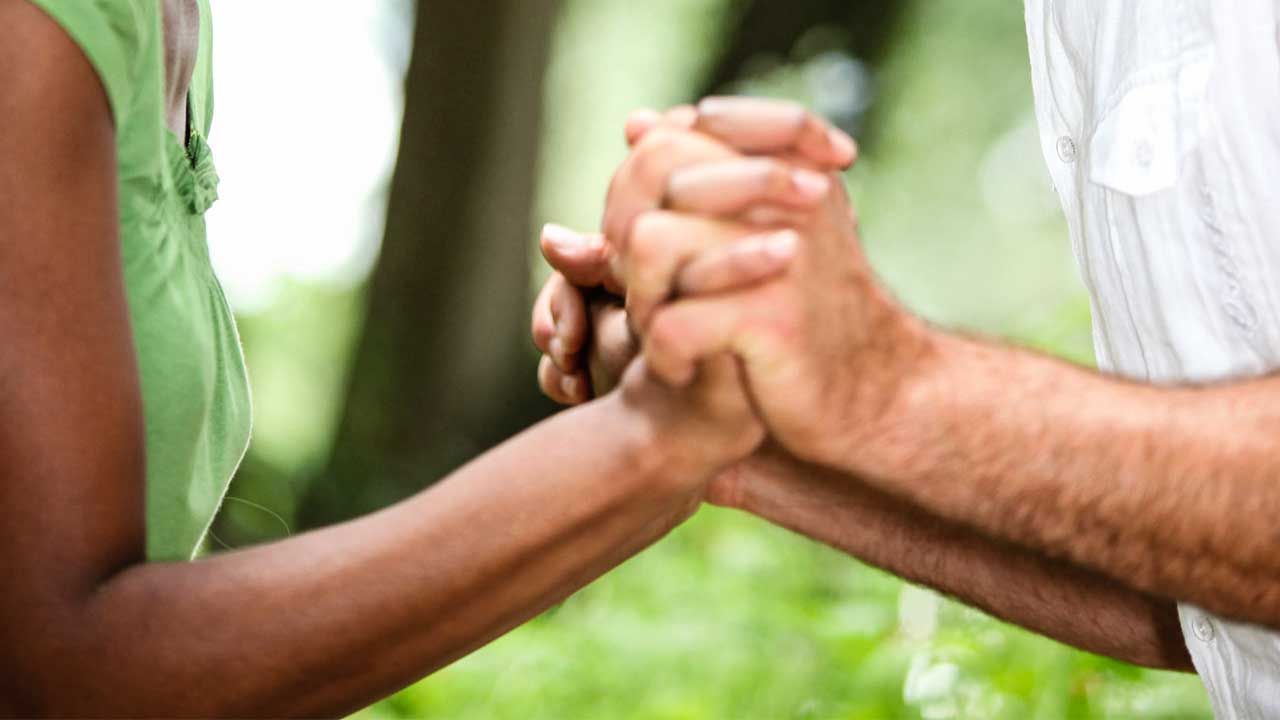 Ein Paar mit unterschiedlichen Hautfarben hält Hände