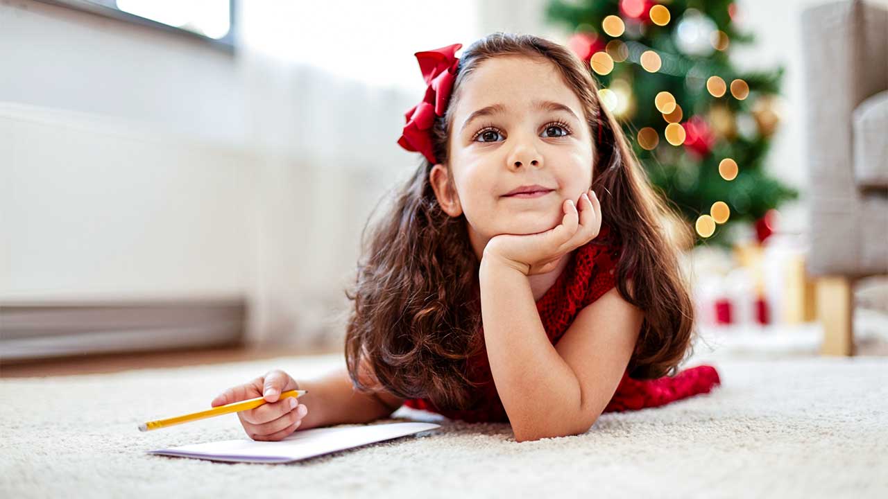 Mädchen liegt mit leerem Papier am Boden und studiert über Weihnachtswünsche nach