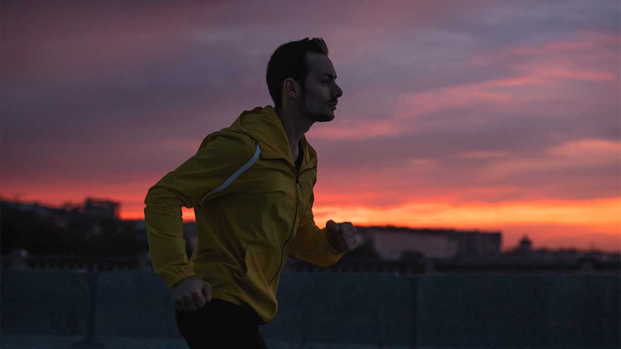 Mann joggt in der Dämmerung bei Sonnenuntergang