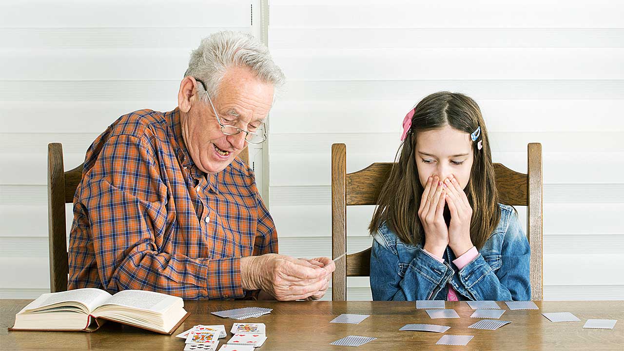 Grossvater und Enkelin spielen zusammen ein Kartenspiel