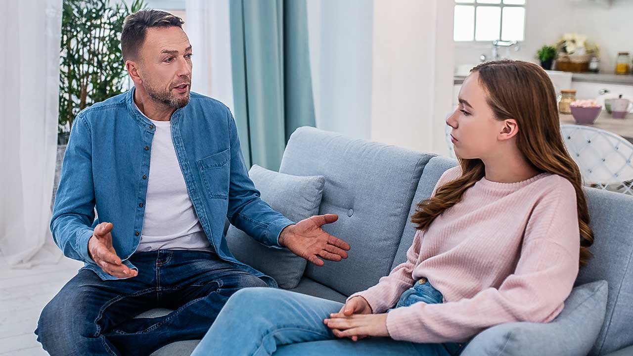 Vater und Tochter sitzen auf einem Sofa und führen ein ernstes Gespräch
