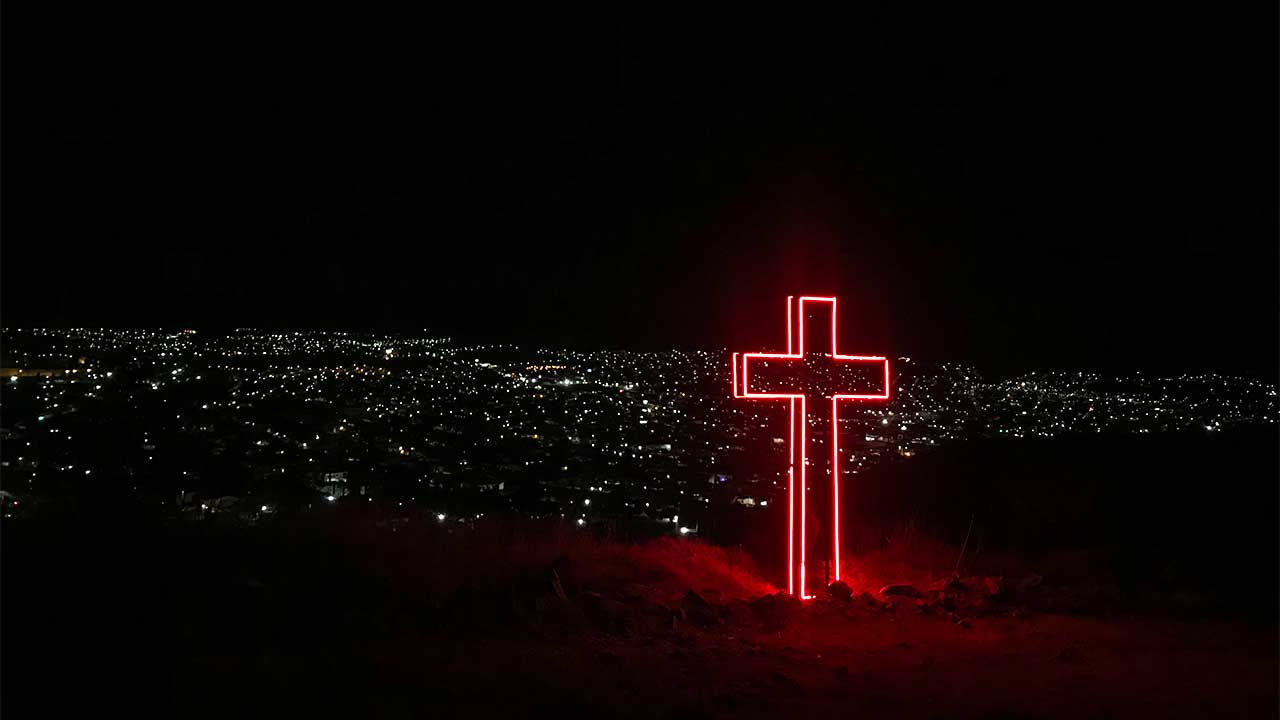 rotes Kreuz in der Nacht über einer mexikanischen Stadt