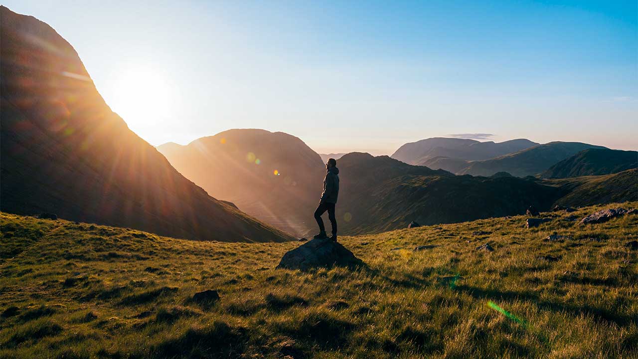 Mann unterwegs in einer gebirgigen Landschaft in Cumbria, England