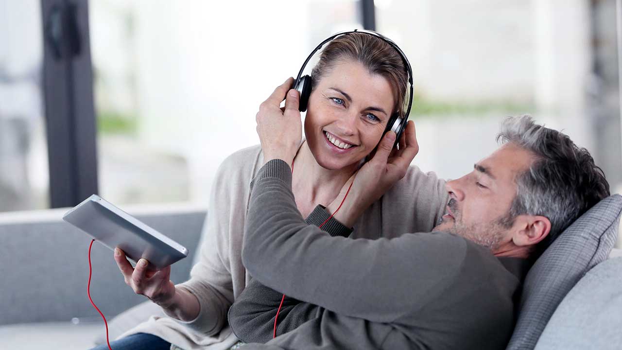 Paar hört auf einem Sofa Musik oder Radio