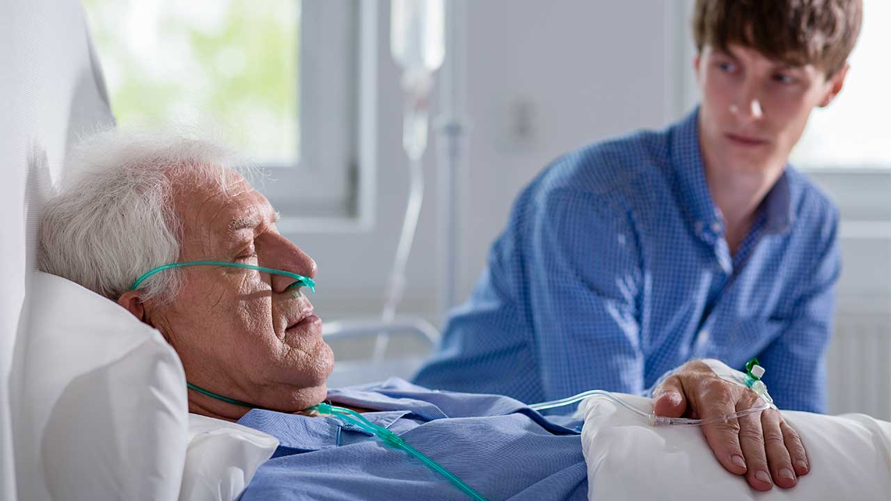 junger Mann zu Besuch im Spital bei einem Senioren, der gerade schläft