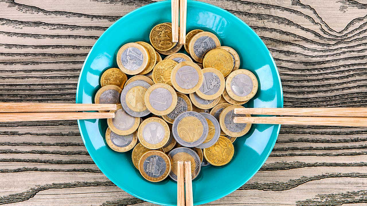 Euro-Münzen auf einem Teller mit Essstäbchen