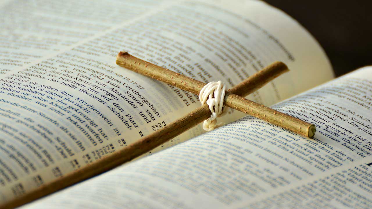 Ein Holzkreuz liegt inmitten einer Bibel