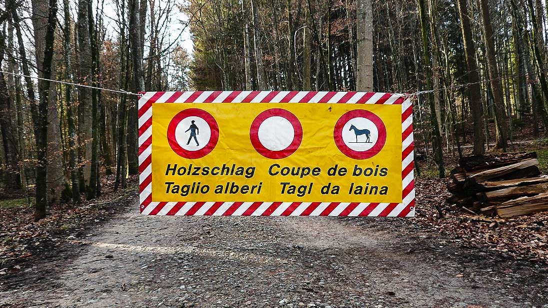 viersprachiges Schild in einem Wald