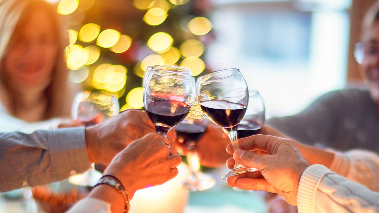 Familie an einem Weihnachtsfest: Hände mit Weinglas prosten sich zu