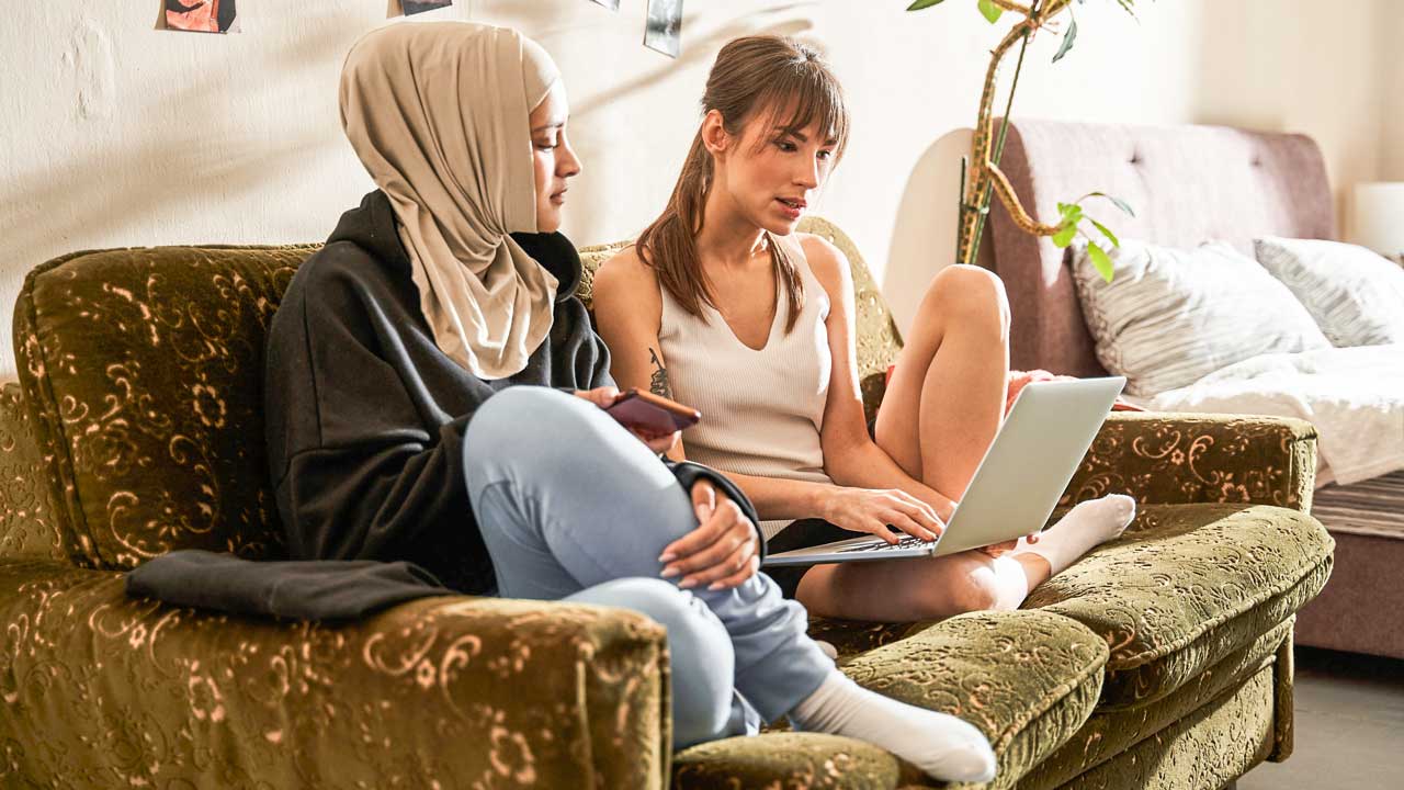 zwei junge Frauen mit einem Laptop, eine davon eine Muslimin