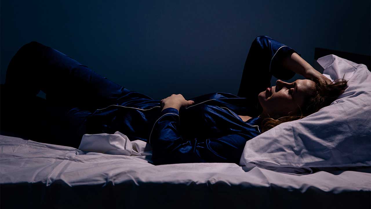 schlaflose Frau liegt nachts in ihrem Bett